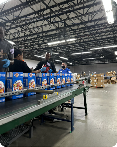 Team members managing packaged goods on a conveyor system inside a large Central Ohio assembly facility, supporting high-volume manufacturing projects.